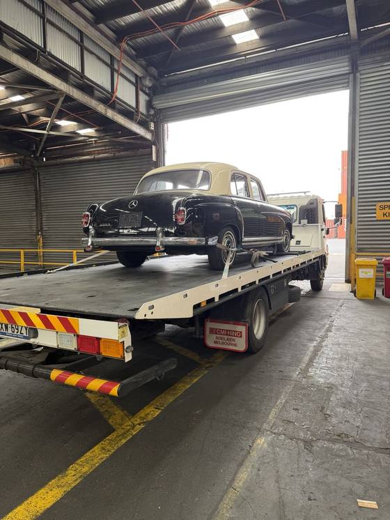 Hilly's truck carrying a restored black and cream classic Mercedes inside a warehouse